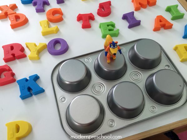 Spelling CVC words with letter magnets on muffin tins from Modern Preschool