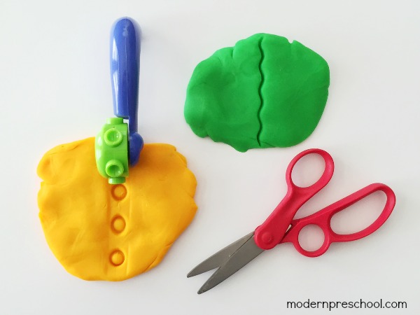 Practice toddler and preschool scissor skills with play dough! A fun, simple way to encourage proper scissor grip and use while cutting with fine motor skills.