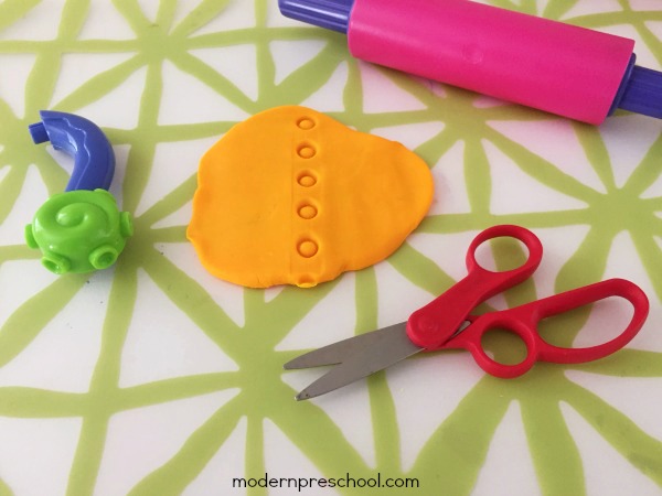 Practice toddler and preschool scissor skills with play dough! A fun, simple way to encourage proper scissor grip and use while cutting with fine motor skills.