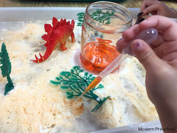 Kids can discover and explore chemical reactions made with baking soda and vinegar in this simple dinosaur and lava themed activity tray!